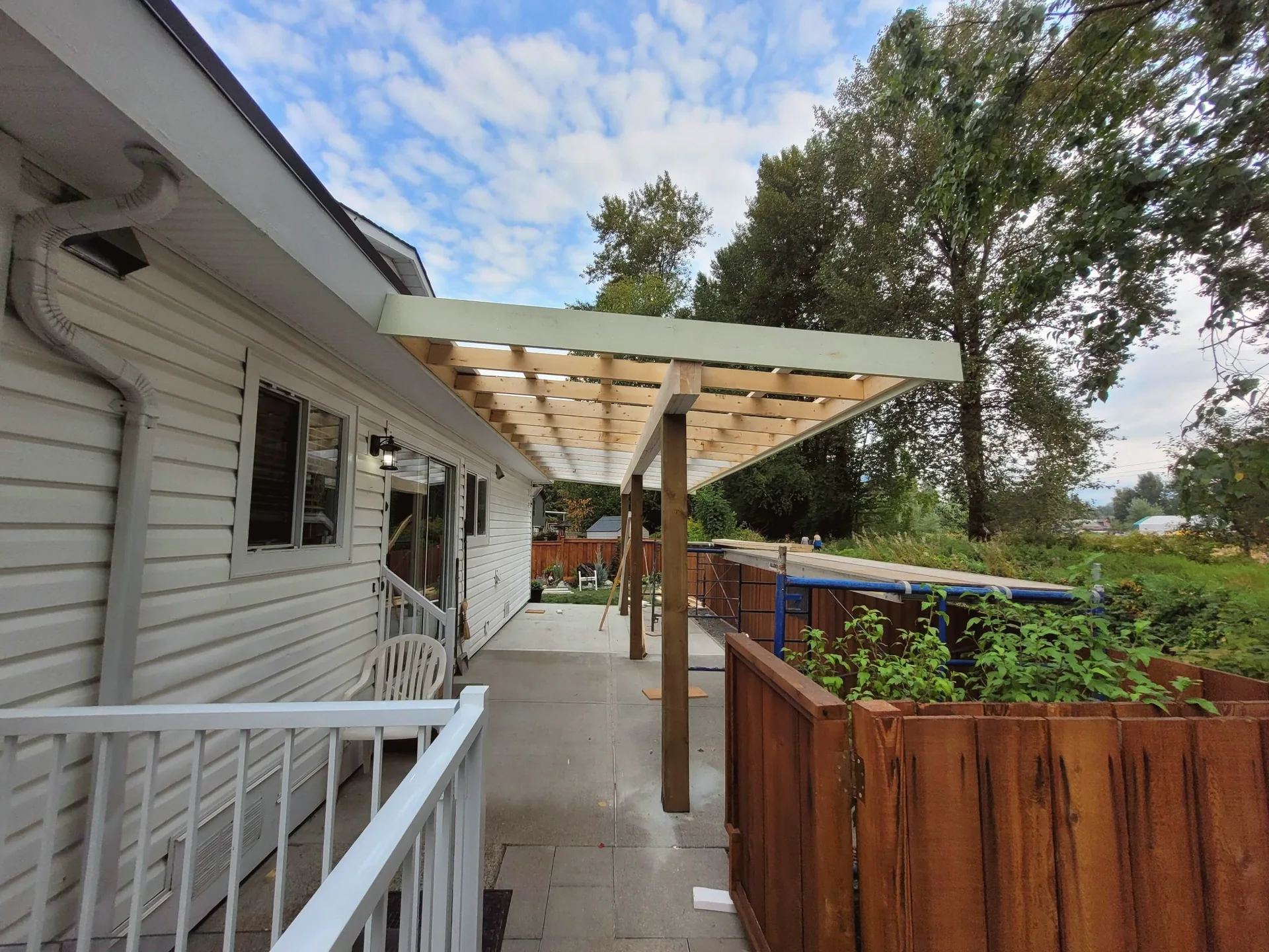 Covered concrete patio and pergola at the side of a home