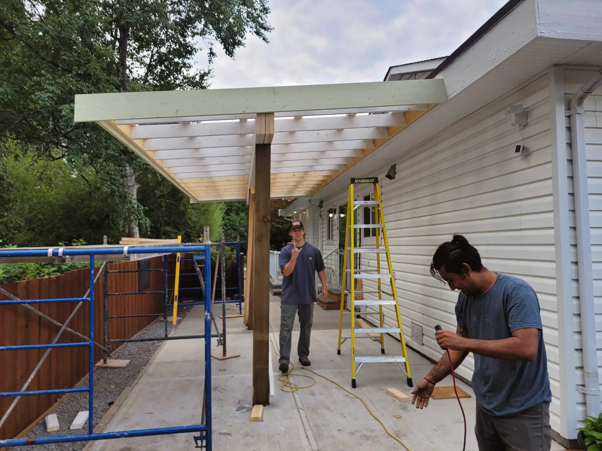 Crew building and detailing a covered pergola over a patio