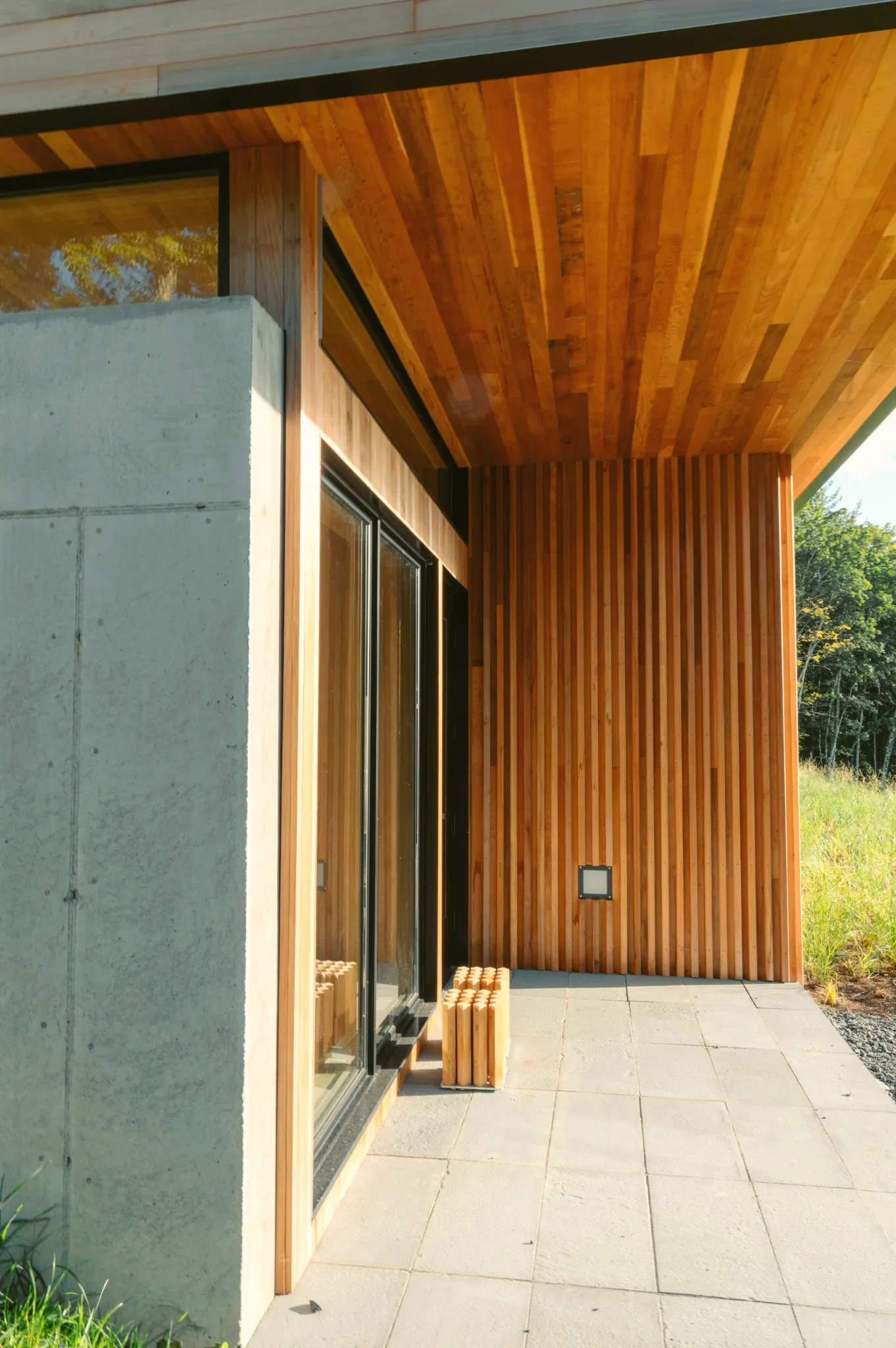 Exterior wood siding and concrete wall meeting at a modern patio
